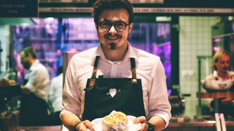 Au restaurant, un serveur souriant nous présente un plat.