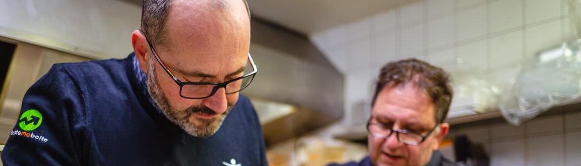 Cédric taille le persil en cuisine avec le chef Rony.