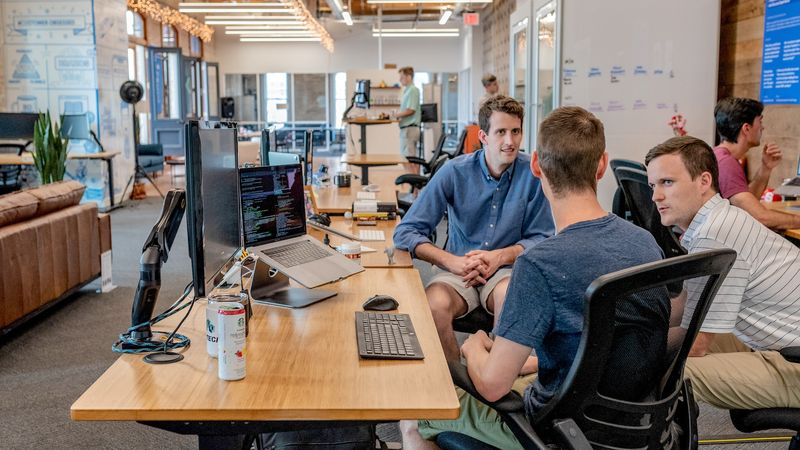 Dans un open space, une équipe de travail discute de la stratégie de croissance de leur entreprise.